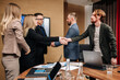 © Vladislav - Business people shaking hands in the meeting room, preparing for the conference, cooperation with clients, shareholders planning a partnership deal in the corporate office.