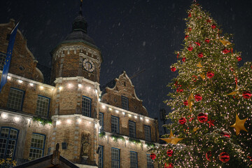 Wall Mural - Spectacular view on the Dusseldorf town hall and Marktplatz Christmas market with a snowcapped Christmas tree. The picture was taken during light snowfall with a sensational night sky.