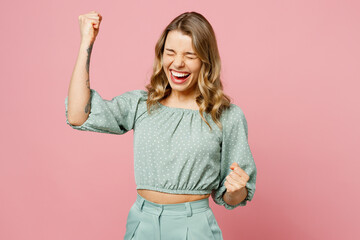 Wall Mural - Young smiling excited fun happy woman she wear casual clothes doing winner gesture celebrate clenching fists say yes isolated on plain pastel light pink background studio portrait. Lifestyle concept.