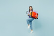 Traveler woman wear casual clothes hold suitcase bag pov play guitar isolated on plain pastel blue background. Tourist travel abroad in free spare time rest getaway. Air flight trip journey concept.