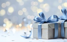 Close Up Of Silver Gift Boxes With Blue Ribbon Bow Tag Over Blurred Bokeh Background With Lights. Christmas Decor. Greeting Festive Image. Copy Space