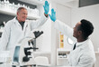 © Talia Mdlungu/peopleimages.com - Science men, high five and together in lab, smile or partnership for goals, results or innovation at job. Senior scientist and mentorship with teamwork, congratulations or success in medical research