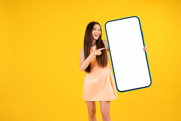 Beautiful Asian woman holding big blank smartphone with empty white screen, showing excellent offer, template for your design