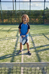 Cheerful boy with racket on playground