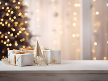 White & Gold Christmas Gifts And Ornaments On Empty Wooden Table With Blurred Bokeh Lights