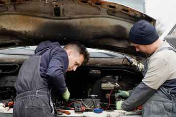 two master auto mechanics diagnosing a van with the hood raised