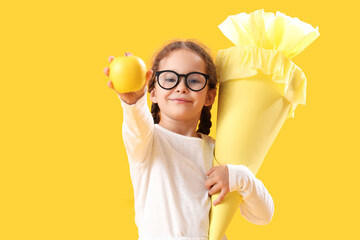 Sticker - Happy little girl in eyeglasses with school cone and fresh apple on yellow background