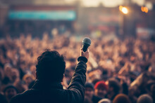 Microphone In The Artist's Hand Against The Background Of A Blurred Crowd Of Spectators