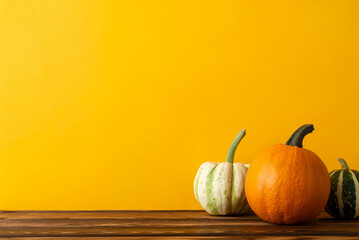 Wall Mural - Embrace the harvest season! A side view shot of a wooden table adorned with a cornucopia of crops, including pumpkin and pattypans, set against orange wall backdrop