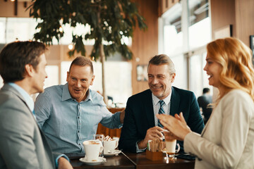 Wall Mural - Group of middle aged business coworkers having a meeting over coffee in a cafe decorated for christmas and the new year holidays