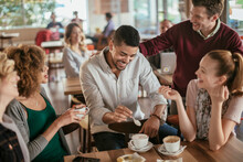 Young And Diverse Group Of People Talking While Having Coffee Together In A Cafe