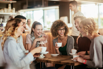 Young and diverse group of friends talking while having coffee together in a cafe