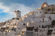 Santorini, Greece - 05 27 2023: Cycladic architecture of Oia, Windmills and white-painted houses in complete harmony with the volcanic scenery