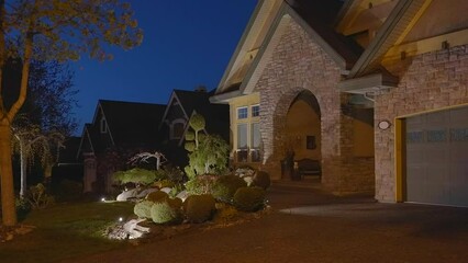 Wall Mural - Establishing shot of two story stucco luxury house with garage door, big tree and nice landscape at night in Vancouver, Canada, North America. Night time on Apr 2023. ProRes 422 HQ.