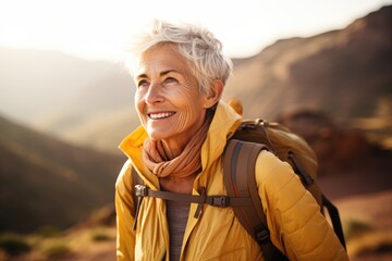 Wall Mural - Smiling portrait of a happy senior woman hiker hiking in the forest and mountains