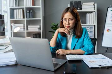 Wall Mural - Stressed, tired, sleepy businesswoman bored from sitting at a desk for long hours and having office syndrome while working with laptop and financial paperwork. office marketing.