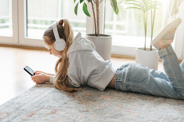 Wall Mural - Little girl listening music lying on the floor