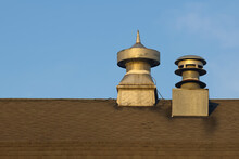 Exterior View Of Air Vent And Chimney On A Old Barn Roof Against Blue Background.