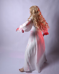  Full length portrait of  scary vampire zombie bride, wearing elegant halloween fantasy costume  dress with bloody red paint splatter. standing walking pose. Isolated on white studio background 