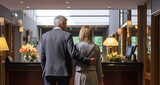Fototapeta Tulipany - Senior couple checking into a hotel, standing by a counter in the lobby. Ready to begin their vacation. Shallow field of view.