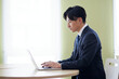 オフィスにてノートパソコンを使用して仕事をする若い日本人ビジネスマン