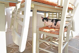 Fototapeta Londyn - beautiful black and white cat sitting on chair at a greek tavern