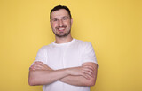 Fototapeta Do przedpokoju - Photo of attractive charming young guy wear white t-shirt arms crossed empty space isolated yellow color background.