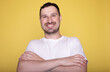© lashkhidzetim - Photo of attractive charming young guy wear white t-shirt arms crossed empty space isolated yellow color background.