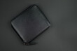 Black leather wallet with zip on a black background. Close up