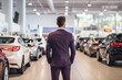Worker in suit at car dealership seen from behind