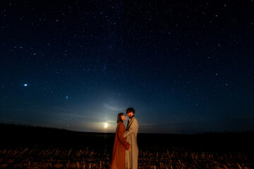 Wall Mural - silhouettes of a couple in love at night against the backdrop of the night starry sky, romantic date