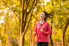 紅葉の中でジョギングをする若い女性