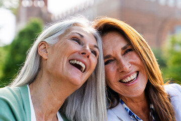 Beautiful senior women meeting outdoors in the city - Two mature female adults friends bonding and having fun while shopping outdoors