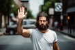 © Jorge Ferreiro - man with a beard and a white t-shirt is raising his hand in a stop sign