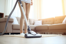 Woman using a vacuum cleaner while cleaning carpet  in the house.