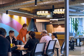 Wall Mural - A diverse team of business experts in a modern glass office, attentively listening to a colleague's presentation, fostering collaboration and innovation.