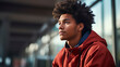 © Dirk - copy space, a closeup photo portrait of handsome afro american teenage guy sitting on a bench on the railway platform.  Waiting for the train to arrive. Travel photo.