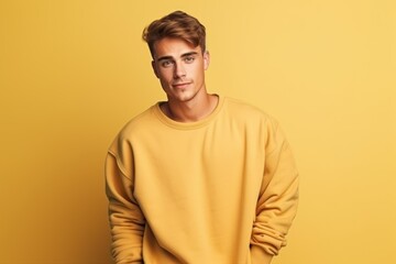 Wall Mural - Isolated Portrait of a Fictional Male Model Wearing a Large Oversized Yellow Colored Sweatshirt on a Plain Blank Background. Generative AI.