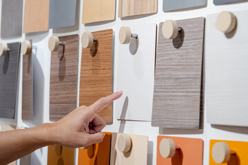 Wall Mural - designer hand pointing at wood samples board on material swatch wall display in library. choosing wo