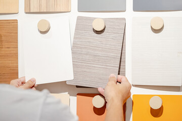 Wall Mural - designer hands compare wood samples board on material swatch wall display in library. choosing woode