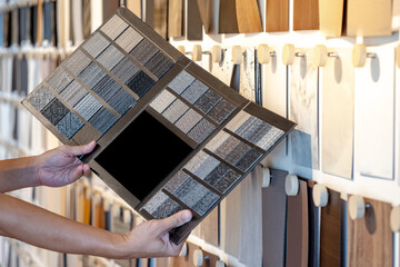 Wall Mural - designer hand holding fabric tile carpet samples catalog in material library. choosing rug flooring 