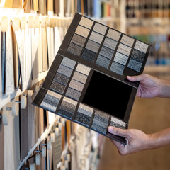 Wall Mural - designer hand holding fabric tile carpet samples catalog in material library. choosing rug flooring 