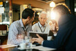 © Marko Geber - Diverse group of bussinessmen using a tablet while having a meeting in a cafe or bar