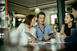© Marko Geber - Diverse group of business coworkers using a smartphone while having a meeting in a cafe or bar