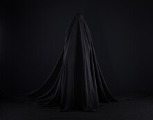 Witch In A Black Cloak On A Black Background