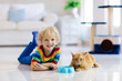 © famveldman - Child playing with cat at home. Kids and pets.