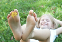 Child feet on green grass, barefoot little girl on meadow, countryside lifestyle, concept of grounding and connecting with nature
