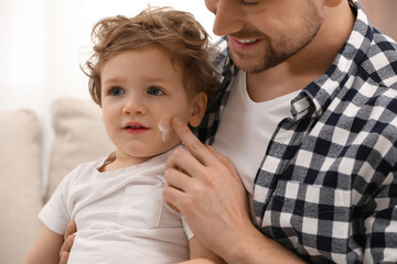 Poster - Father applying ointment onto his son`s cheek indoors