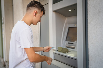 man teenage student using credit card and withdraw cash at the ATM