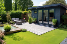 View Of A Back Garden With Artificial Grass, Grey Paving Slab Patio, Summer House Garden Timber Outbuilding, Fish Pond